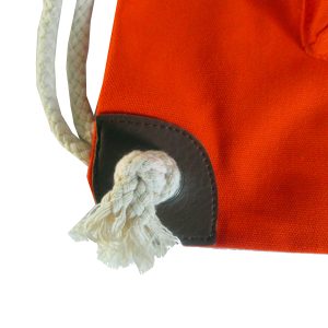 Brown reinforced leather corner and metal eyelet with white cotton rope on orange bag