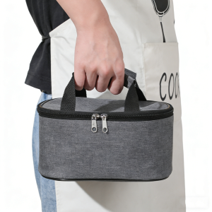 Person holding a grey insulated lunch bag by its woven handles