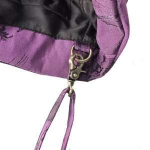 Antique brass metal clasp and hook hardware detail on purple jacquard bag