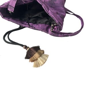 Open purple jacquard bucket bag showing black interior lining and decorative layered tassel