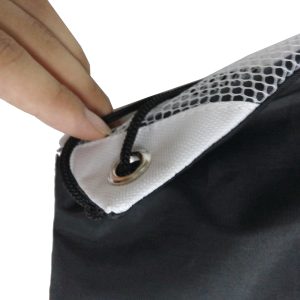 Hand touching white reinforced corner patch with metal eyelet on drawstring bag