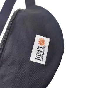 Close-up of custom woven label on black waist bag with orange sun and text