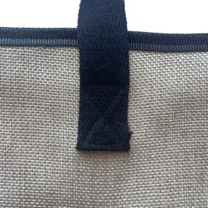 Close-up of black woven webbing handle attachment on beige woven bag