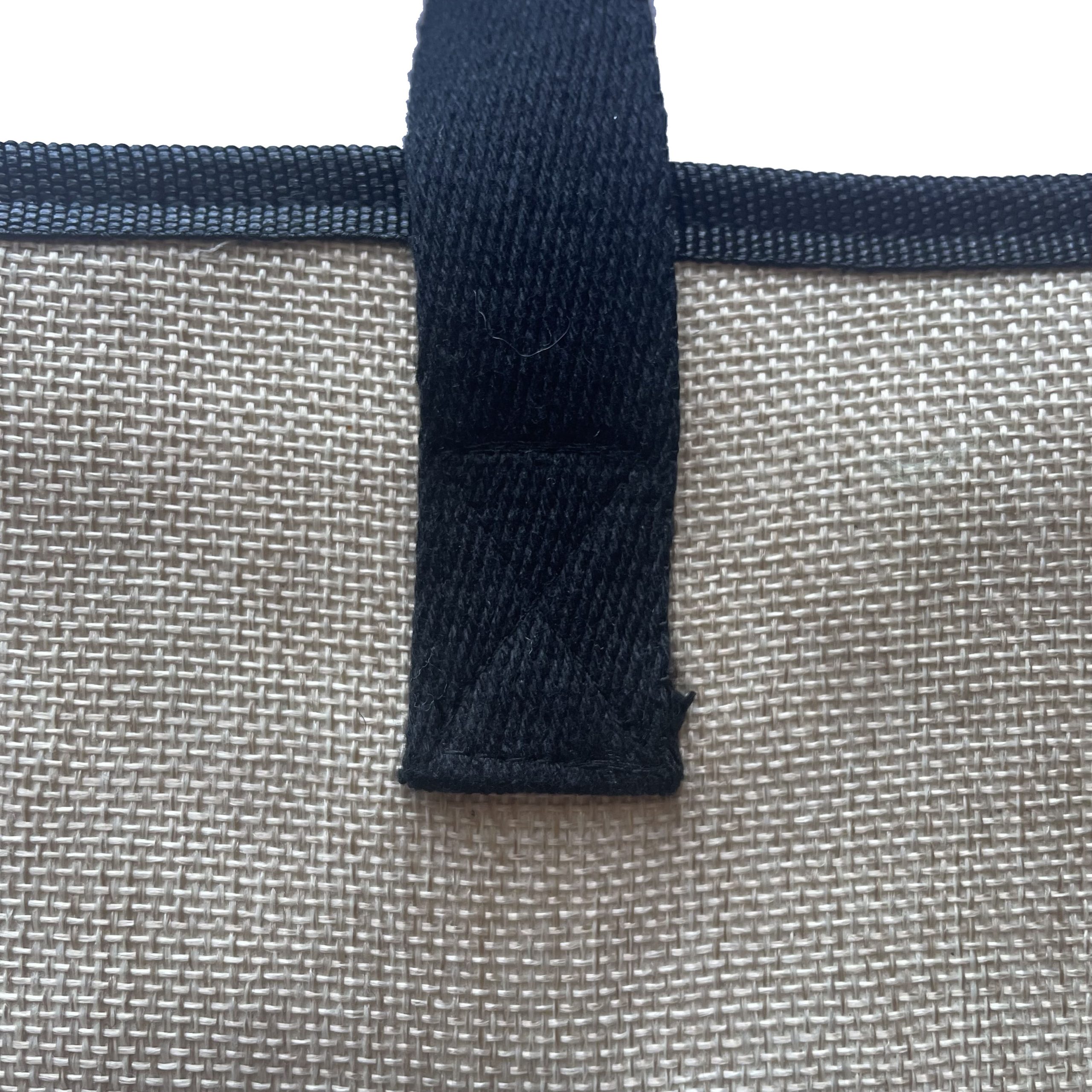 Close-up of black woven webbing handle attachment on beige woven bag