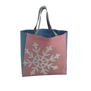 Pink and blue color-block tote bag with grey woven handles and snowflake pattern
