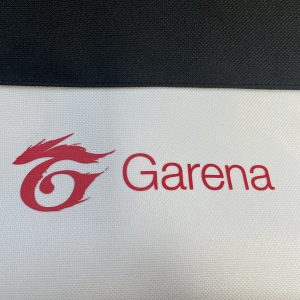 Close-up of red Garena logo printed on white bottom panel of tote bag