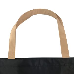 Beige woven handle attachment detail and stitching on black tote bag