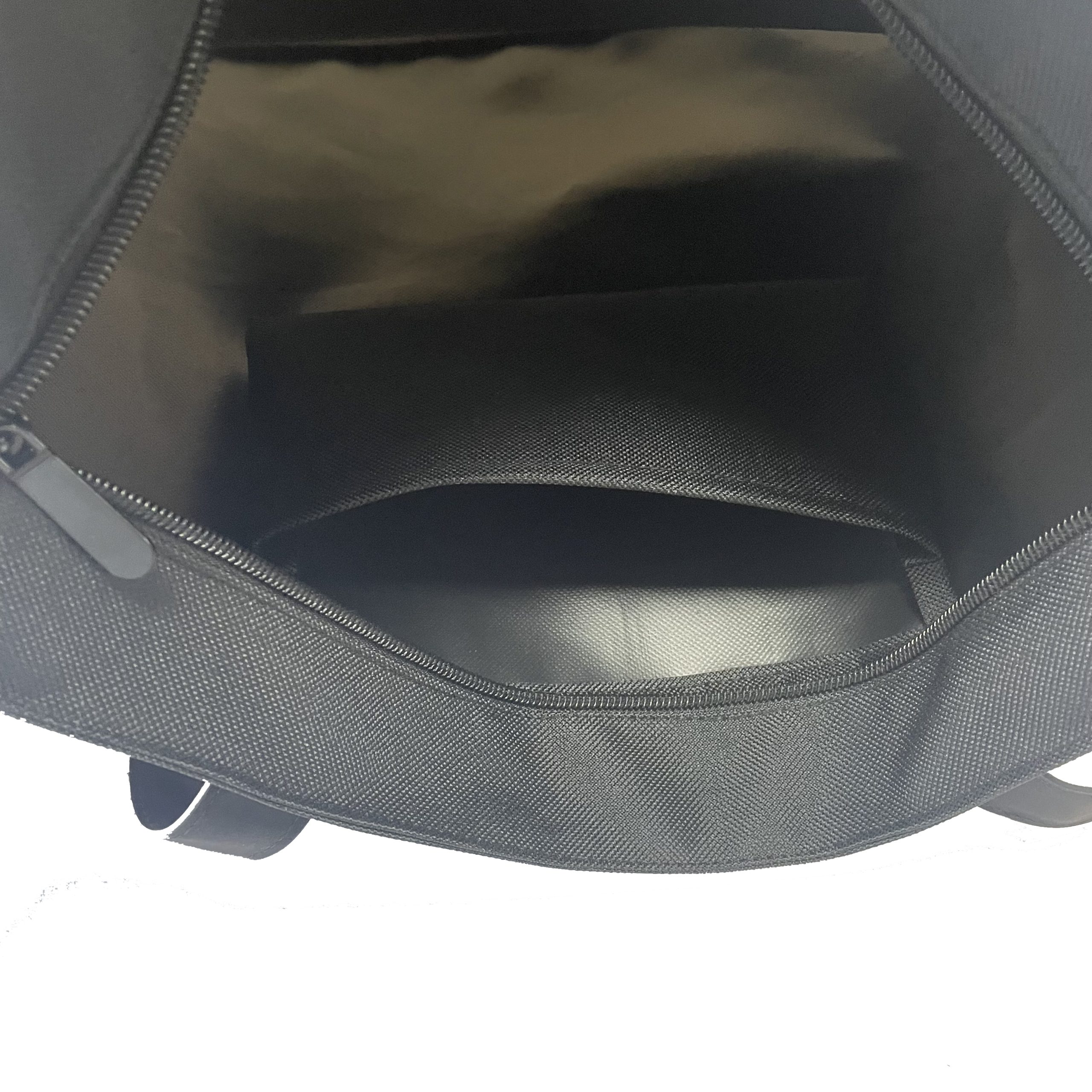 Interior detail of beige woven tote bag showing zipper pocket and black lining