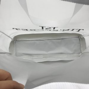 Inner zipper pocket detail inside white mesh tote bag